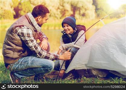 tourism, travel and hike concept - happy father and son hiking and setting up tent outdoors. happy father and son setting up tent outdoors