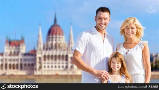 tourism, travel and people concept - happy family over house of parliament in budapest background. happy family over house of parliament in budapest