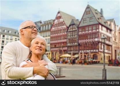 tourism, travel and people concept - happy senior couple hugging over frankfurt am main city background. senior couple hugging over frankfurt background