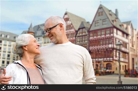 tourism, travel and people concept - happy senior couple hugging over frankfurt am main city background. senior couple hugging over frankfurt background
