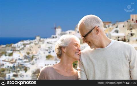 tourism, travel and people concept - happy senior couple over oia town on santorini island background. happy senior couple over santorini island