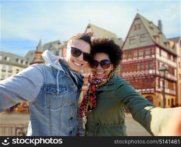 tourism, travel and people concept - happy teenage international couple taking selfie over frankfurt am main city street background. happy couple taking selfie in frankfurt city