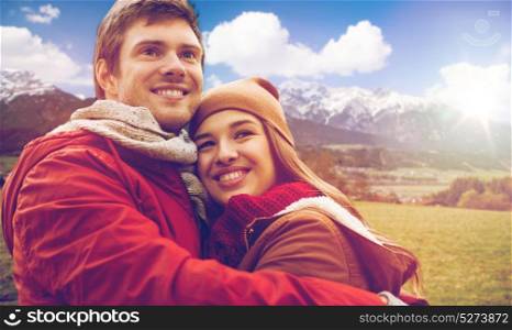 tourism, travel and people concept - happy young couple hugging over alps mountains background. happy young couple hugging over alps mountains