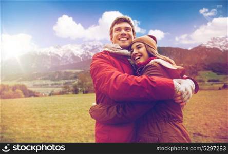 tourism, travel and people concept - happy young couple hugging over alps mountains background. happy couple hugging over alps mountains