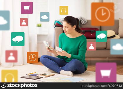 tourism, travel, finances and people concept - happy young woman with money, tablet pc computer and map at home over multimedia icons. happy woman with money and travel map at home