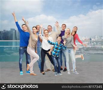 tourism, travel, generation and people concept - group of smiling men, women and boy having fun and waving hands over singapore city waterside background