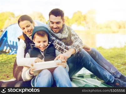 tourism, travel, hike and technology concept - happy family with tablet pc computer and tent at camp site. happy family with tablet pc and tent at camp site