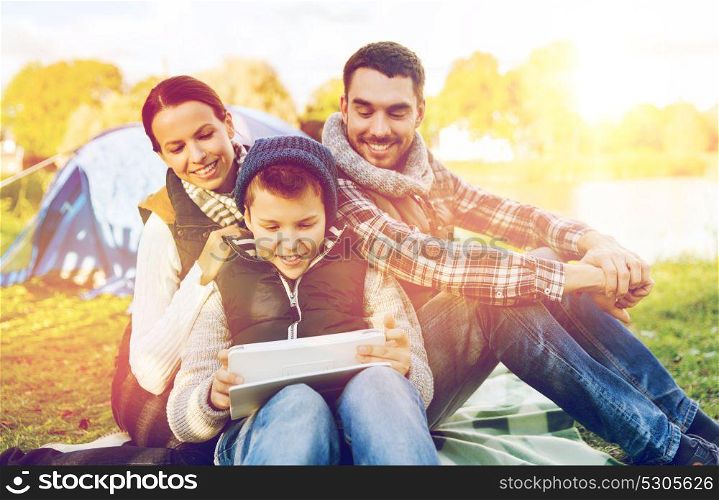 tourism, travel, hike and technology concept - happy family with tablet pc computer and tent at camp site. happy family with tablet pc and tent at camp site