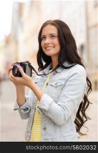 tourism, travel, leisure, holidays and friendship concept - smiling teenage girl with camera taking picture on street