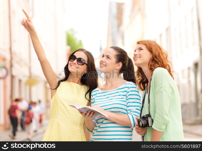 tourism, travel, leisure, holidays and friendship concept - smiling teenage girls with city guide and camera outdoors