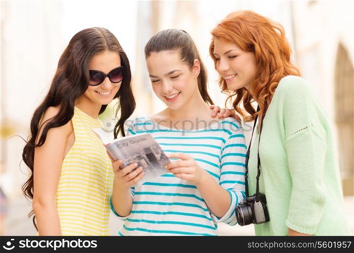 tourism, travel, leisure, holidays and friendship concept - smiling teenage girls with city guide and camera outdoors