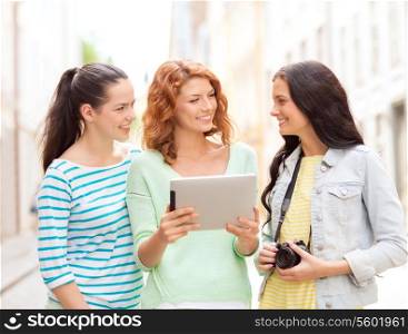 tourism, travel, leisure, holidays and friendship concept - smiling teenage girls with witch tablet pc computer and camera outdoors