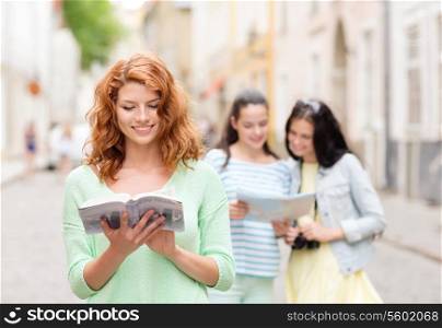tourism, travel, leisure, holidays and friendship concept - smiling teenage girls with city guide, map and camera outdoors