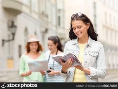 tourism, travel, leisure, holidays and friendship concept - smiling teenage girls with city guide, map and camera outdoors