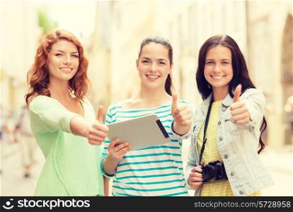 tourism, travel, leisure, holidays and friendship concept - smiling teenage girls with tablet pc computer and camera showing thumbs up