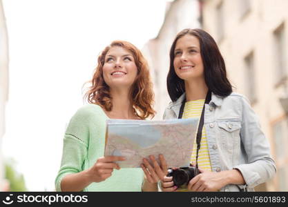 tourism, travel, leisure, holidays and friendship concept - smiling teenage girls with map and camera outdoors