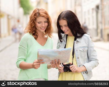 tourism, travel, leisure, holidays and friendship concept - smiling teenage girls with map and camera outdoors