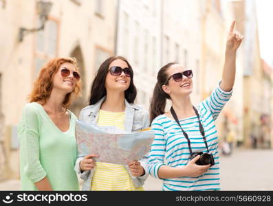 tourism, travel, leisure, holidays and friendship concept - smiling teenage girls with map and camera outdoors