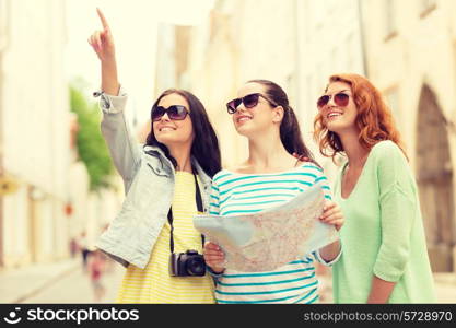 tourism, travel, leisure, holidays and friendship concept - smiling teenage girls with map and camera outdoors