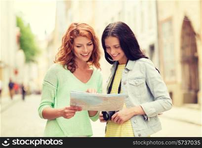 tourism, travel, leisure, holidays and friendship concept - smiling teenage girls with map and camera outdoors