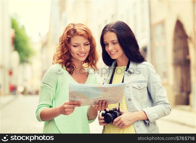 tourism, travel, leisure, holidays and friendship concept - smiling teenage girls with map and camera outdoors
