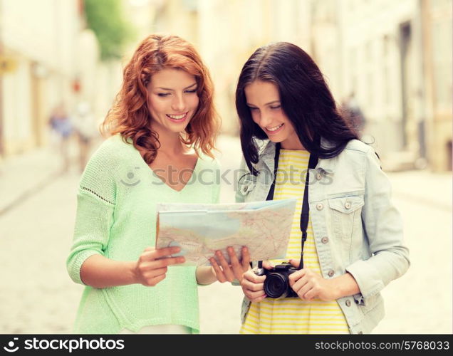 tourism, travel, leisure, holidays and friendship concept - smiling teenage girls with map and camera outdoors