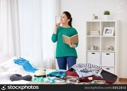 tourism, travel, people and luggage concept - happy young woman with notebook planning her trip at home. woman with notebook planning her trip at home