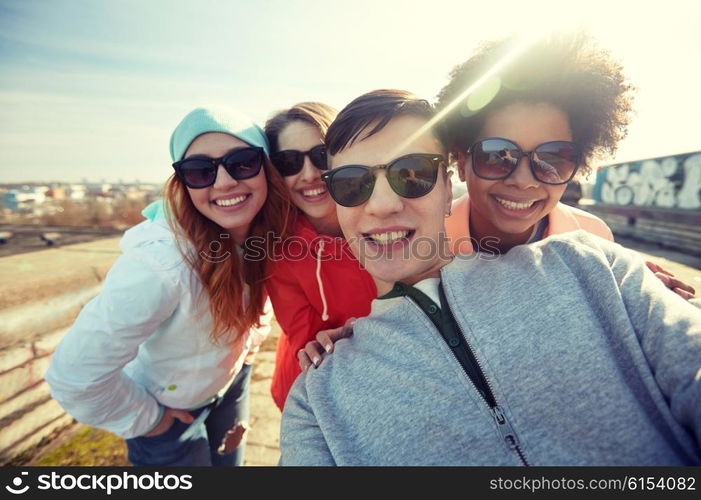 tourism, travel, people, leisure and technology concept - group of smiling teenage friends taking selfie on city street