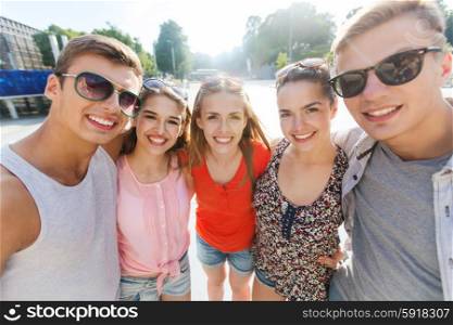 tourism, travel, people, leisure and technology concept - group of smiling teenage friends taking selfie outdoors