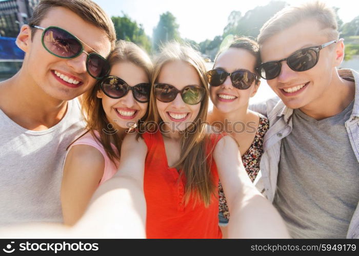 tourism, travel, people, leisure and technology concept - group of smiling teenage friends taking selfie outdoors