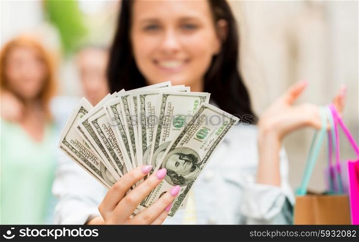 tourism, travel, sale and consumerism concept - close up of happy woman with shopping bags and dollar money on city street