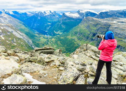 Tourism vacation and travel. Female tourist taking photo with camera, enjoying Geiranger fjord and mountains landscape from Dalsnibba Plateau viewpoint, Norway Scandinavia.. Tourist taking photo from Dalsnibba viewpoint Norway