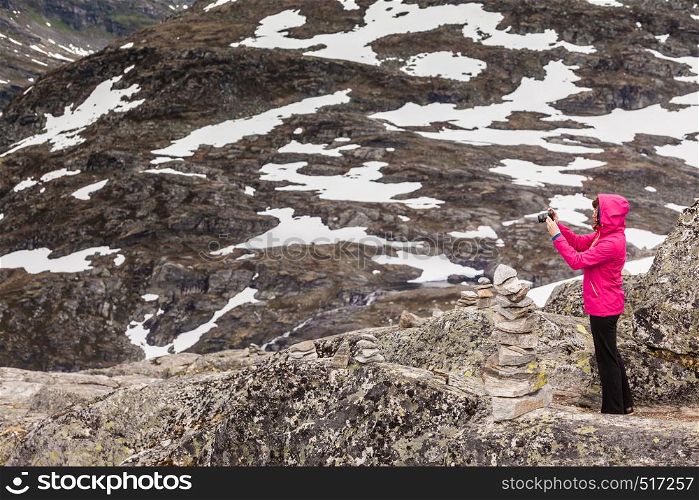 Tourism vacation and travel. Female tourist taking photo with camera, enjoying mountains landscape from Dalsnibba viewpoint, Norway Scandinavia.. Tourist taking photo from Dalsnibba viewpoint Norway