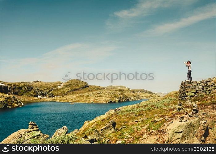 Tourism vacation and travel. Female tourist taking photo with camera, enjoying scenic summer landscape, Norway Scandinavia. National tourist route Aurlandsfjellet. Tourist taking photo in norwegian nature