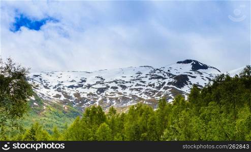Tourism vacation and travel. Mountains landscape at summer and snowcapped mountain tops in the background, Norway, Scandinavia.. Mountains summer landscape in Norway.