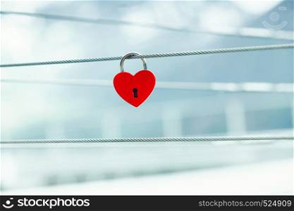 Tourism vacation and travel. Red love heart shaped lock padlock on bridge outdoor, blurred background. Red love lock padlock on bridge outdoor