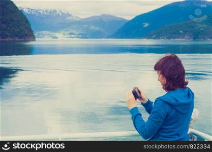 Tourism vacation and travel. Tourist woman on cruise ship enjoying fjord view, taking photo with camera. Norway Scandinavia Europe. Norddalsfjorden as seen from ferry.. Tourist woman on liner taking photo, Norway