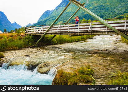 Tourism vacation and travel. Woman tourist relaxing on bridge, looking at mountains landscape in norwegian village Oppstryn, Sogn og Fjordane county. Norway Scandinavia.. Tourist relaxing on bridge in village Oppstryn Norway