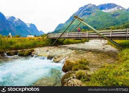 Tourism vacation and travel. Woman tourist relaxing on bridge, looking at mountains landscape in norwegian village Oppstryn, Sogn og Fjordane county. Norway Scandinavia.. Tourist relaxing on bridge in village Oppstryn Norway