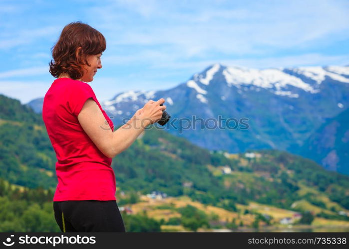 Tourism vacation and travel. Woman tourist taking photo with camera, enjoying mountains fjords view in Jostedalsbreen National Park, Oppstryn (Stryn), Sogn og Fjordane county. Norway Scandinavia.. Tourist taking photo at norwegian fjord