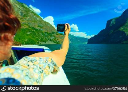 Tourism vacation and travel. Woman tourist taking photo with camera, view from deck of ship on fjord Sognefjord in Norway, Scandinavia.