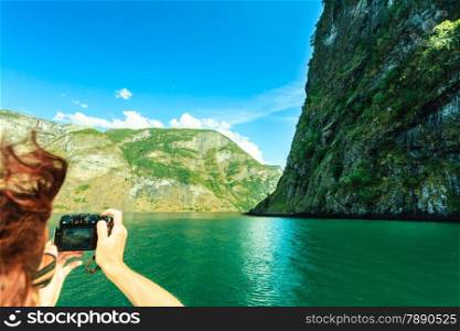 Tourism vacation and travel. Woman tourist taking photo with camera, view from deck of ship on fjord Sognefjord in Norway, Scandinavia.