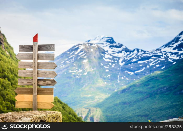 Tourism vacation and travel. Wooden signpost in mountains landscape at summer, snowcapped mountain tops in the background, Norway, Scandinavia.. Wooden sign in norwegian mountains.
