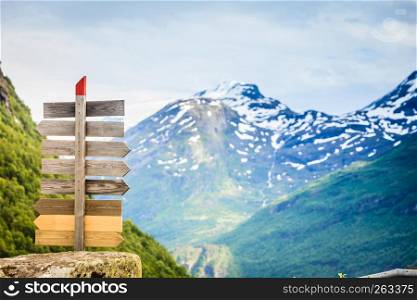 Tourism vacation and travel. Wooden signpost in mountains landscape at summer, snowcapped mountain tops in the background, Norway, Scandinavia.. Wooden sign in norwegian mountains.
