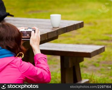 Tourist adult woman taking picture using professional camera. Photographing mug on bench outdoor.. Tourist adult woman taking picture of mug
