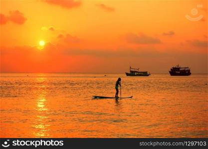 tourist are enjoy with surf board on sea in evening time before sun set.silhouette people in relax time with seascape,cloud sky nature background.