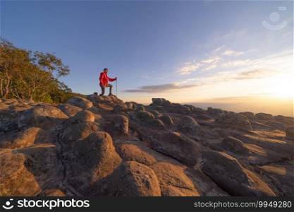 Tourist Asian man trekking, traveling at dry rocks stone in Lan Hin Pum, Phu Hin Rong Kla National Park, Phitsanulok Province, Thailand. Mountains peak with park landscape. Tourist attraction. People