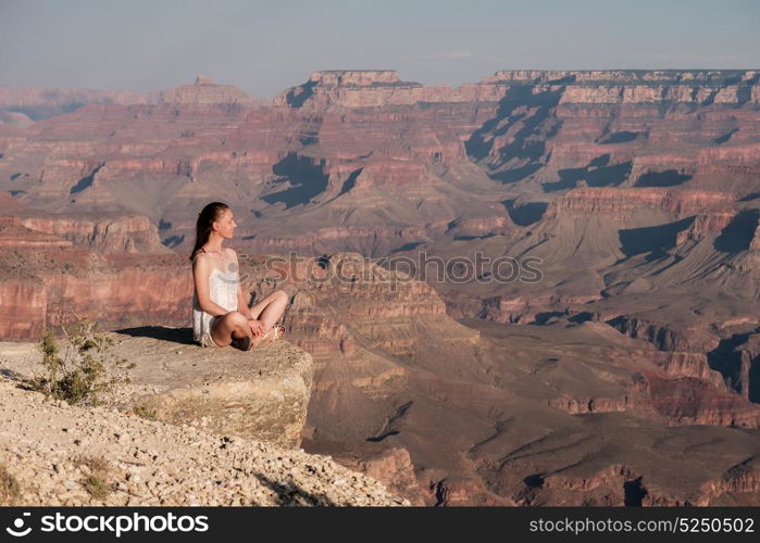 Tourist at Grand Canyon sitting on the rock edge, Arizona, USA