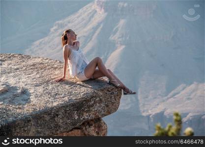 Tourist at Grand Canyon sitting on the rock edge, Arizona, USA