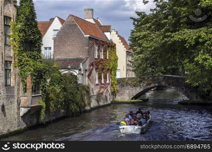 Tourist boat on the canals of the Begijnhof area of the city of Bruges in Belgium. The historic city centre is a UNESCO World Heritage Site.